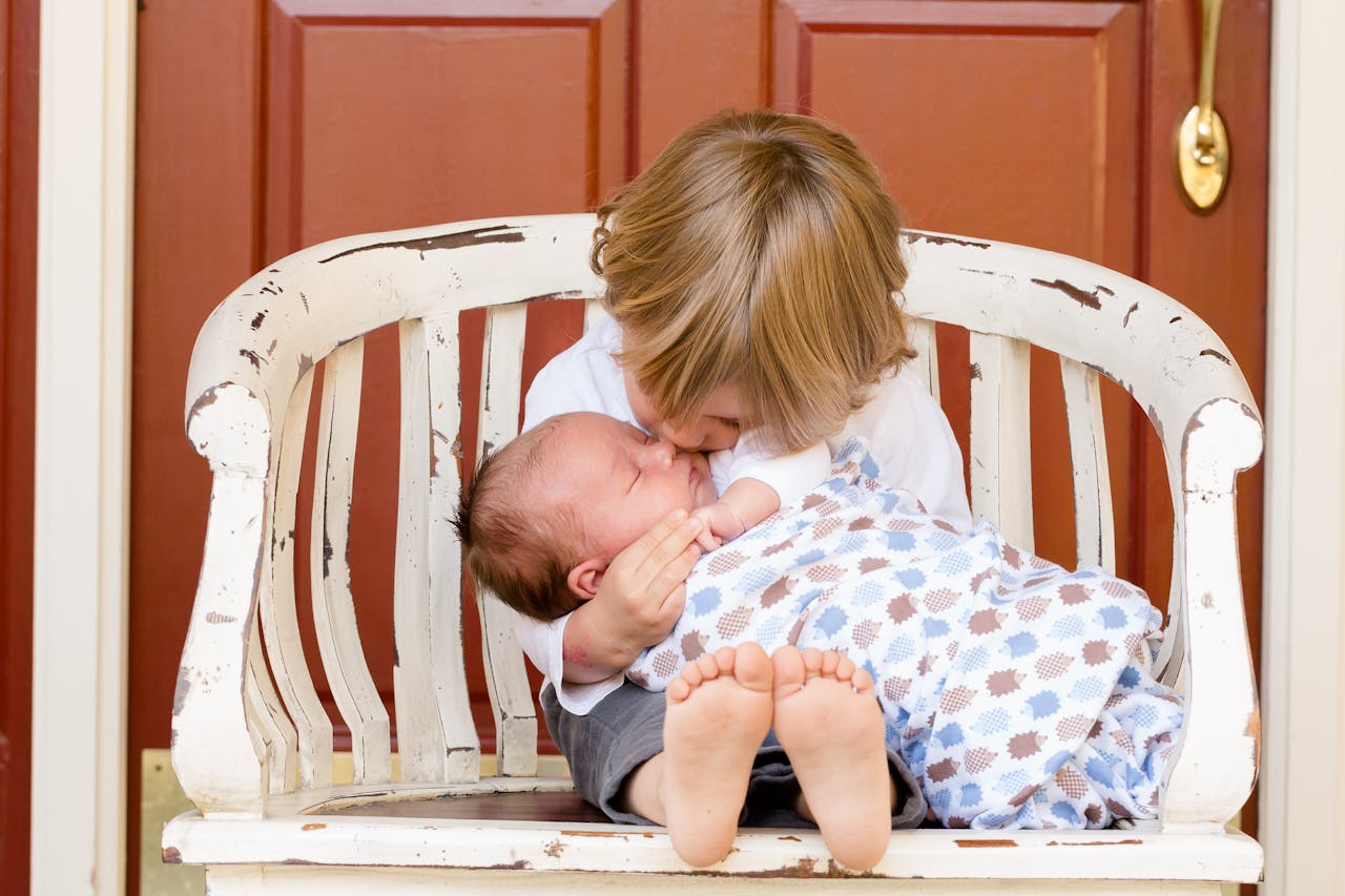 Services A tender moment captured between an older sibling and newborn, embracing love and family bonds.
