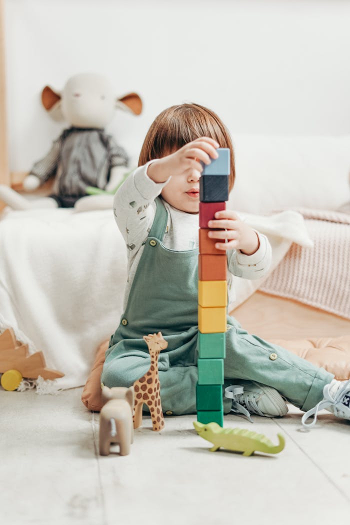Home A cute child stacks colorful wooden blocks while playing indoors, surrounded by toys.